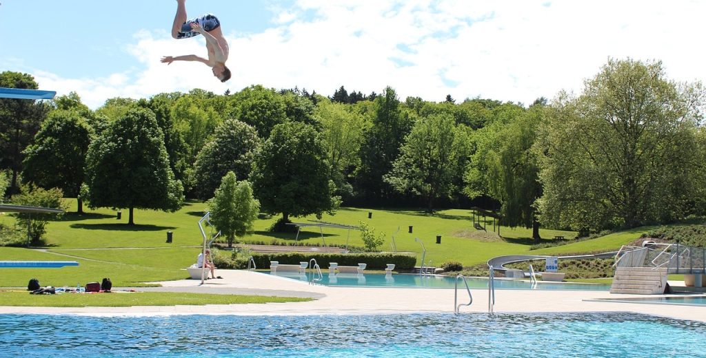 Ein Junge sprint von einem Sprungbrett in einem privatem Freibad an einem Sommertag - Angsa-Robotics bietet die Lösung gegen kleinteiligen Müll